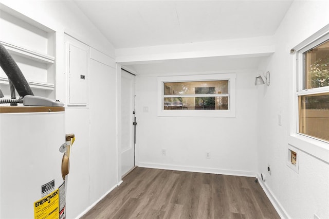 interior space featuring wood finished floors, baseboards, hookup for an electric dryer, electric panel, and water heater