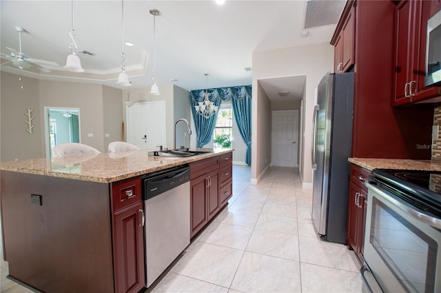 kitchen featuring a center island with sink, ceiling fan with notable chandelier, hanging light fixtures, stainless steel appliances, and a sink