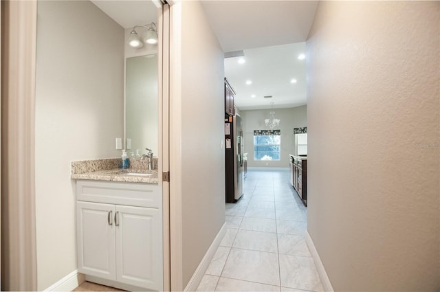 corridor featuring a notable chandelier, baseboards, and a sink