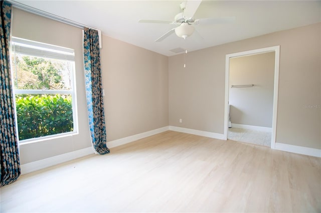 unfurnished room with baseboards, attic access, wood finished floors, and a ceiling fan