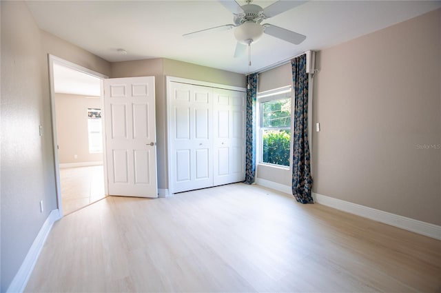 unfurnished bedroom with a ceiling fan, wood finished floors, baseboards, and a closet