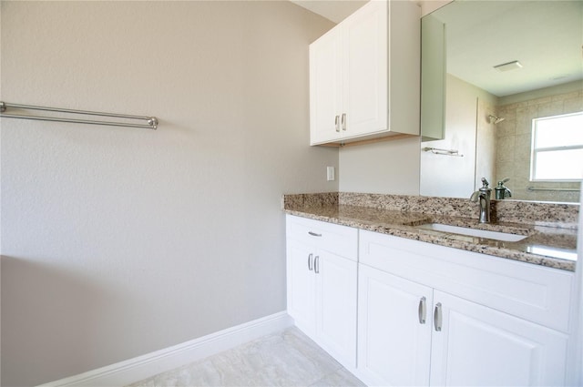 full bathroom featuring baseboards, tiled shower, and vanity