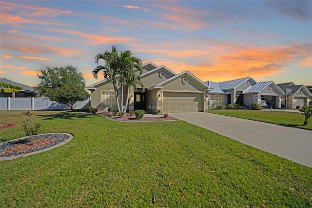 view of front of home featuring stucco siding, driveway, fence, a front yard, and a garage