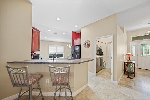 kitchen featuring visible vents, reddish brown cabinets, refrigerator with ice dispenser, and a peninsula