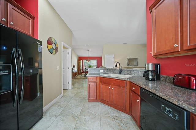 kitchen featuring baseboards, dark stone countertops, a peninsula, black appliances, and a sink