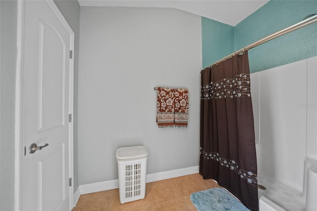 bathroom with tile patterned floors, curtained shower, baseboards, and vaulted ceiling