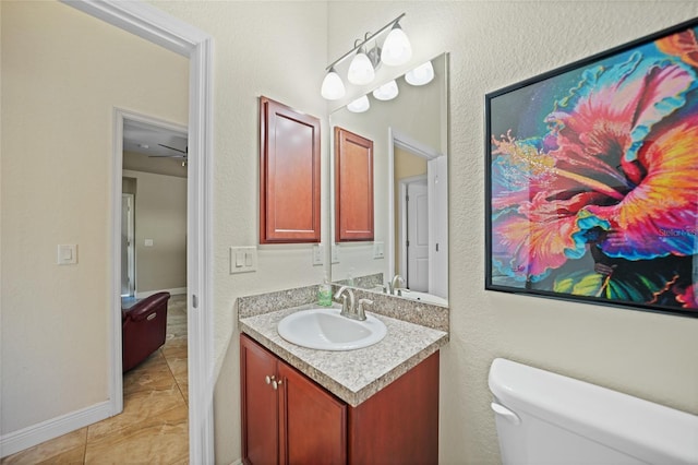 half bath featuring tile patterned flooring, toilet, vanity, and baseboards