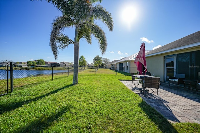 view of yard featuring a patio area, a water view, and fence