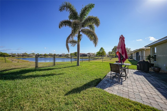 view of yard featuring a patio area, a water view, and fence
