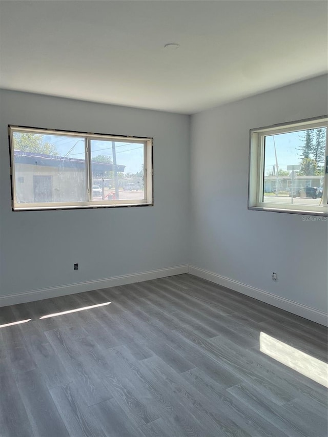 empty room featuring baseboards and dark wood finished floors
