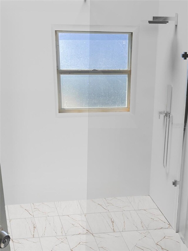 bathroom with walk in shower, marble finish floor, and a healthy amount of sunlight