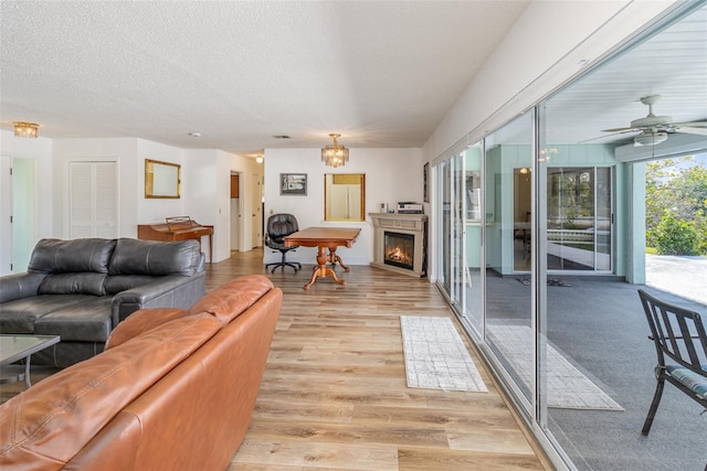 535 Ramblewood St, Port Charlotte, FL 33953 - living area with a lit fireplace, light wood-style floors, ceiling fan, and a textured ceiling
