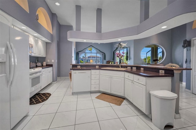 412 Panarea Dr, Punta Gorda, FL 33950 - kitchen with white appliances, light tile patterned floors, a sink, white cabinets, and dark countertops
