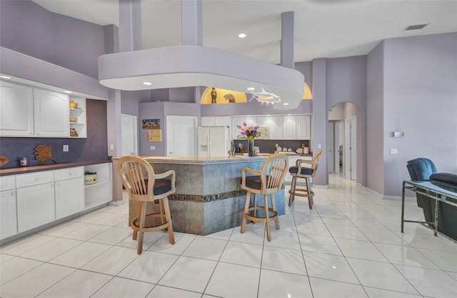 412 Panarea Dr, Punta Gorda, FL 33950 - kitchen with visible vents, light tile patterned flooring, arched walkways, white refrigerator with ice dispenser, and a kitchen breakfast bar