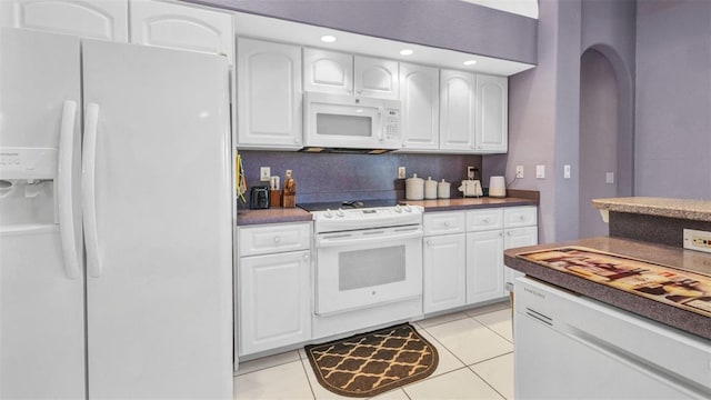412 Panarea Dr, Punta Gorda, FL 33950 - kitchen with white appliances, light tile patterned flooring, white cabinets, dark countertops, and tasteful backsplash