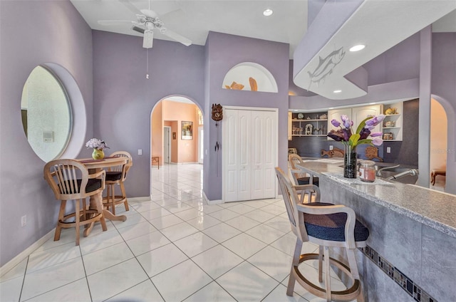 412 Panarea Dr, Punta Gorda, FL 33950 - kitchen featuring a ceiling fan, open shelves, arched walkways, a breakfast bar area, and light tile patterned flooring