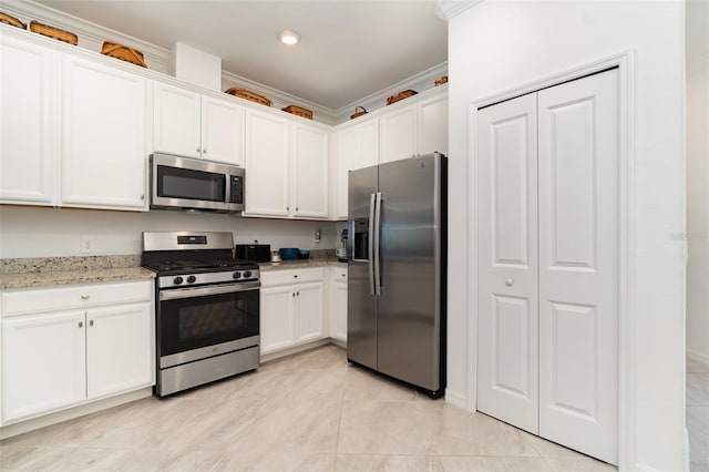 kitchen with light stone countertops, white cabinets, ornamental molding, and appliances with stainless steel finishes