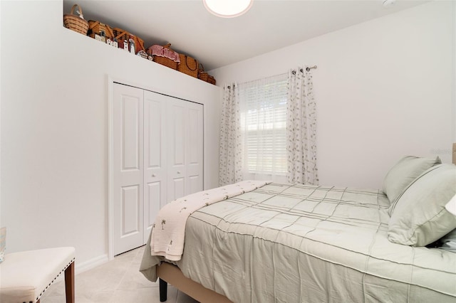 bedroom featuring a closet, baseboards, and light tile patterned floors