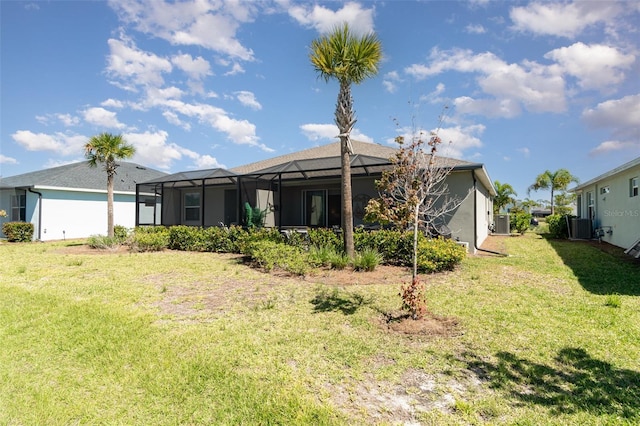 rear view of property with glass enclosure, stucco siding, central AC unit, and a yard