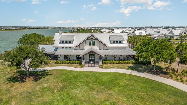 modern farmhouse with a chimney, a water view, and a front lawn