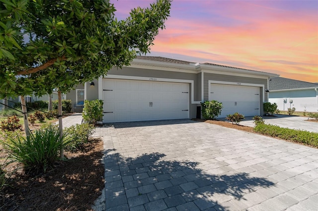 view of front of house with decorative driveway, a garage, and stucco siding