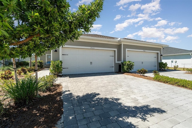 view of front of property with decorative driveway, an attached garage, and stucco siding