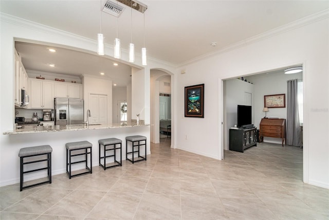 kitchen featuring a breakfast bar, a peninsula, stainless steel appliances, white cabinets, and arched walkways
