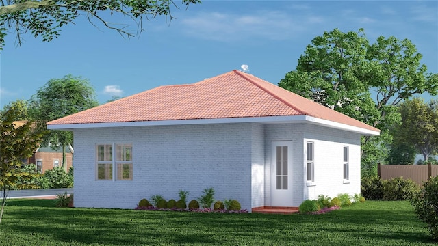 view of side of property with fence, a lawn, brick siding, and a tiled roof
