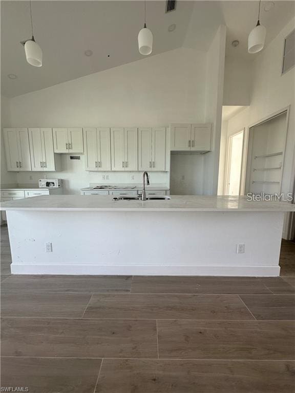 8136 Sweden Blvd, Punta Gorda, FL 33982 - kitchen with a spacious island, light countertops, dark wood-style flooring, high vaulted ceiling, and a sink