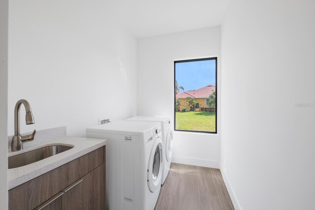 24259 Peppercorn Rd, Punta Gorda, FL 33955 - laundry room featuring independent washer and dryer, a sink, cabinet space, light wood-style floors, and baseboards