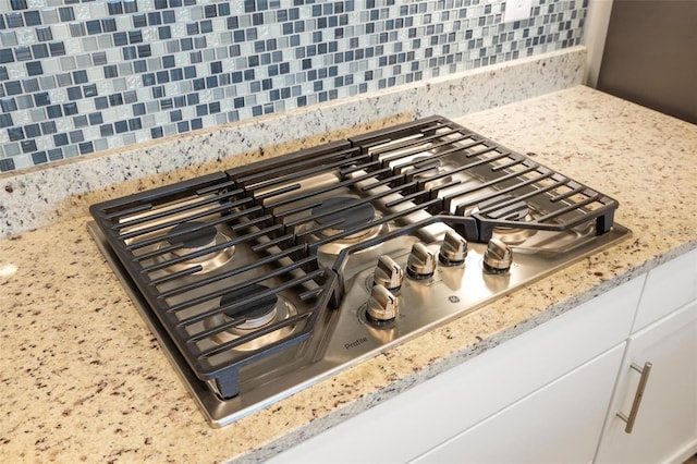 15931 Sugar Hill Dr, Punta Gorda, FL 33982 - interior details with tasteful backsplash, white cabinetry, stainless steel gas stovetop, and light stone countertops