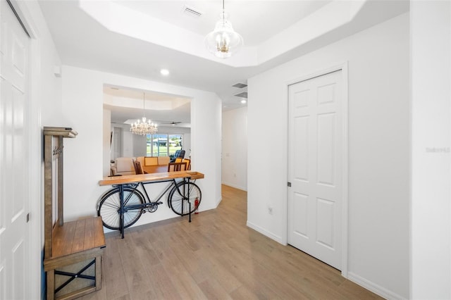15931 Sugar Hill Dr, Punta Gorda, FL 33982 - hallway with a raised ceiling, an inviting chandelier, visible vents, and light wood-style flooring