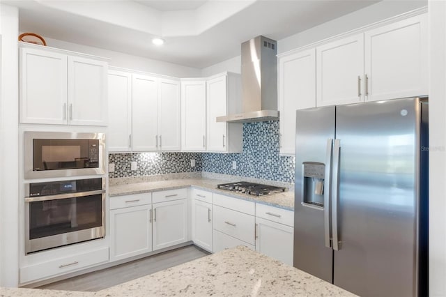 15931 Sugar Hill Dr, Punta Gorda, FL 33982 - kitchen with light wood-style floors, light stone countertops, wall chimney range hood, white cabinets, and stainless steel appliances