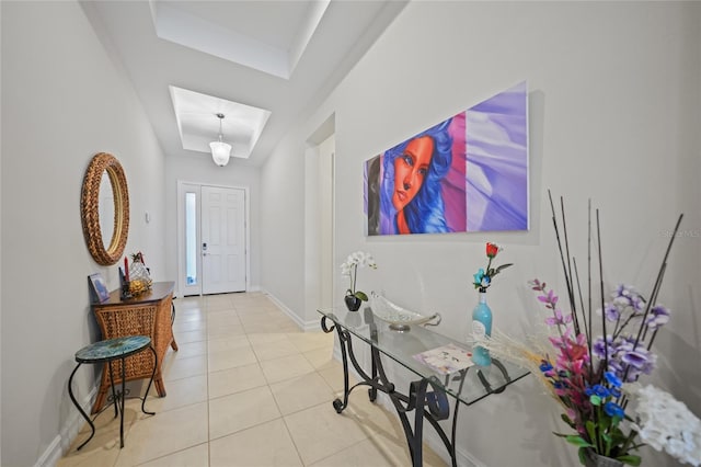 foyer entrance with light tile patterned floors, a tray ceiling, and baseboards