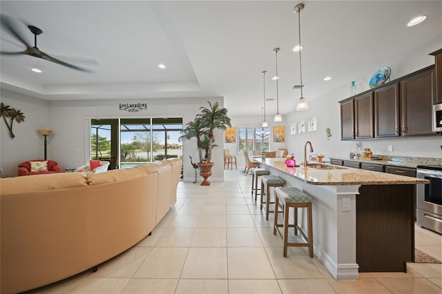 kitchen featuring open floor plan, a sink, light tile patterned floors, and appliances with stainless steel finishes