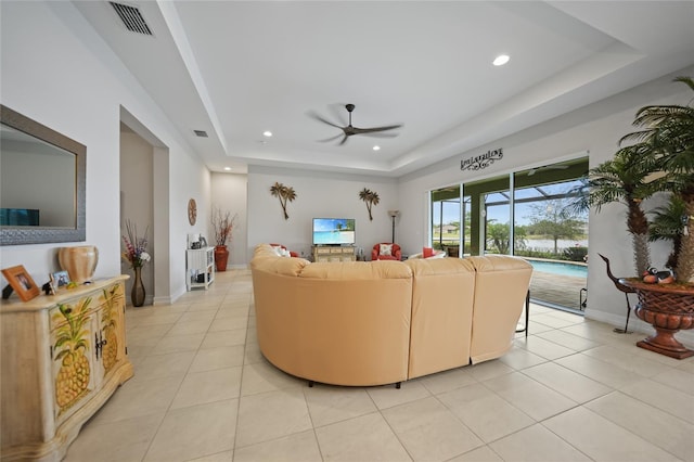 living area with a ceiling fan, a raised ceiling, light tile patterned floors, and recessed lighting