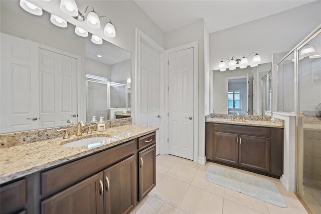 full bath featuring a shower stall, tile patterned floors, a sink, and two vanities