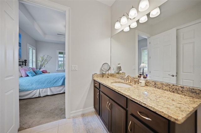 bathroom featuring vanity, a tray ceiling, baseboards, tile patterned floors, and connected bathroom
