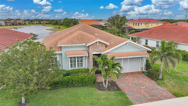 view of front of house with decorative driveway, a garage, a tile roof, a residential view, and stucco siding