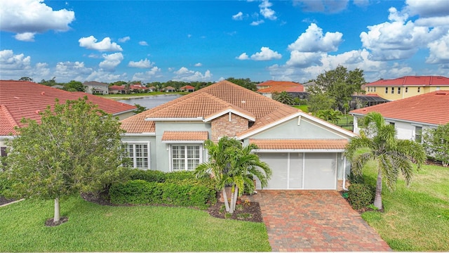 view of front facade with stucco siding, a tiled roof, decorative driveway, a front lawn, and a garage