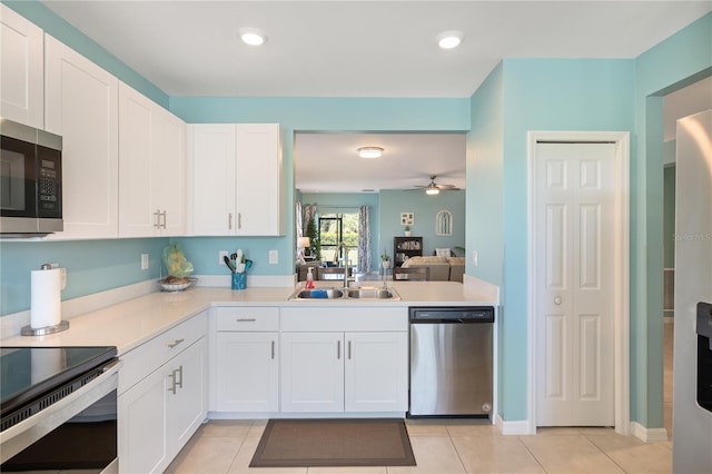 kitchen with light tile patterned floors, white cabinets, a sink, light countertops, and stainless steel appliances