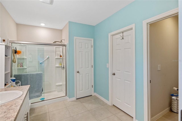 full bath featuring tile patterned flooring, baseboards, a shower stall, and vanity