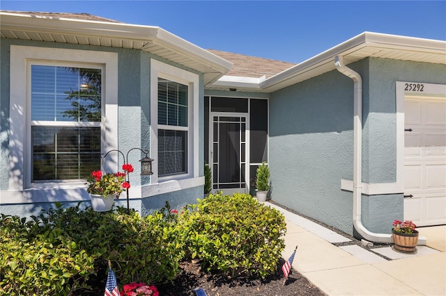 doorway to property with an attached garage and stucco siding