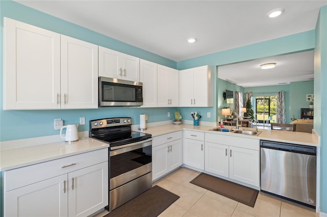 kitchen with white cabinets, a sink, light countertops, appliances with stainless steel finishes, and light tile patterned flooring