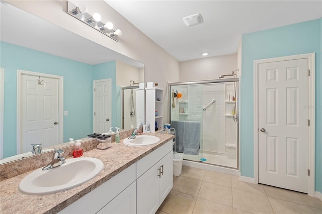 bathroom featuring a sink, tile patterned floors, double vanity, and a stall shower