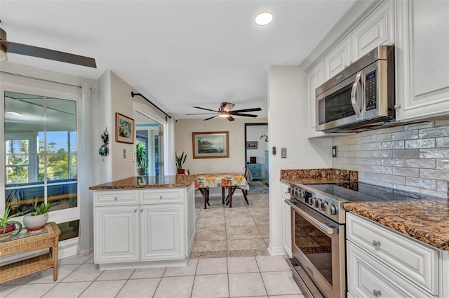 kitchen with stainless steel appliances, decorative backsplash, white cabinetry, dark stone countertops, and recessed lighting