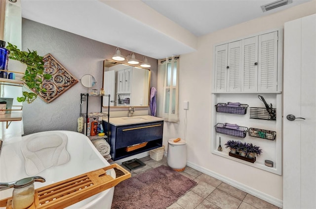 full bathroom with a freestanding bath, tile patterned floors, vanity, and baseboards