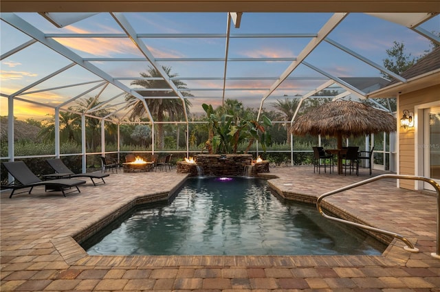 9990 SW Peace River St, Arcadia, FL 34269 - pool at dusk featuring an outdoor pool, an outdoor fire pit, a patio area, and glass enclosure