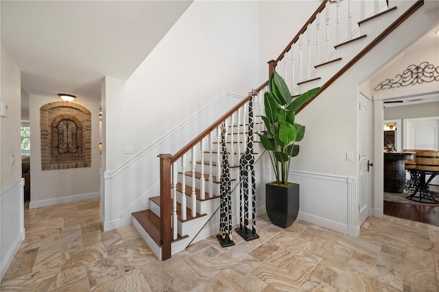 9990 SW Peace River St, Arcadia, FL 34269 - staircase featuring wainscoting, stone finish flooring, and a decorative wall