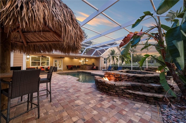 9990 SW Peace River St, Arcadia, FL 34269 - pool at dusk with a ceiling fan, a patio, glass enclosure, an outdoor hangout area, and an outdoor pool